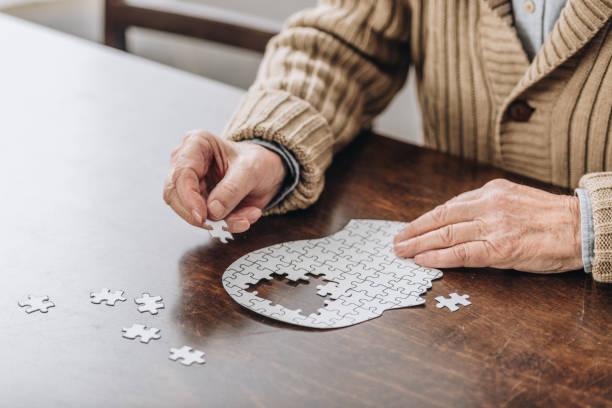 Elderly person working on a skull shaped jigsaw puzzle