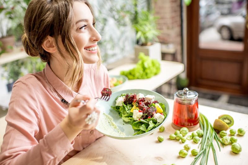 Young woman eating a salad from a plate